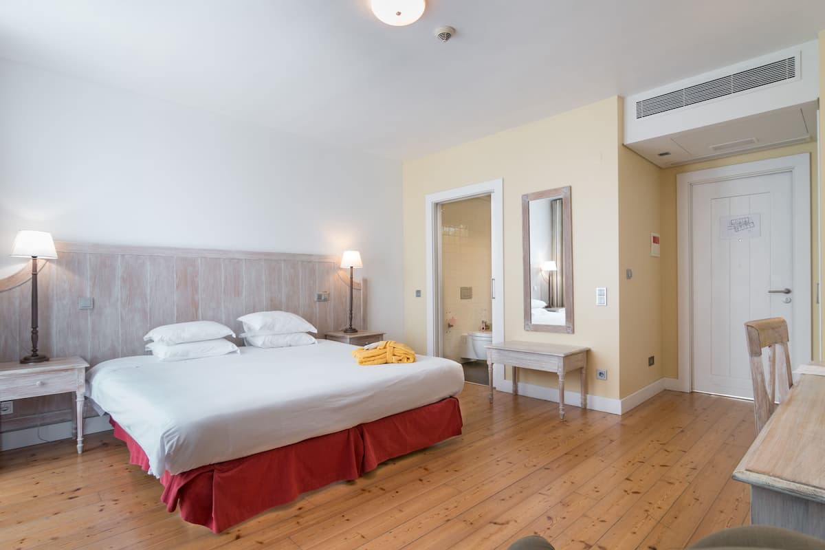 A bedroom with a bed, bedside tables, a mirror, a desk, and a chair.