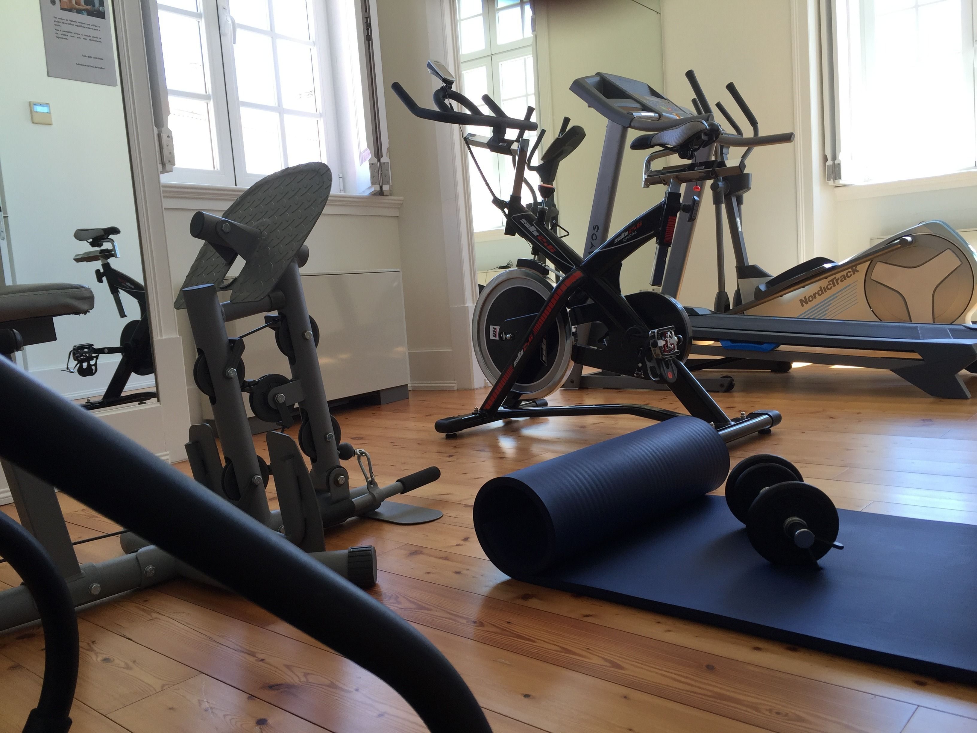 Un gimnasio con diverso equipo de ejercicio, incluyendo cintas de correr, bicicletas estáticas y máquinas de pesas.