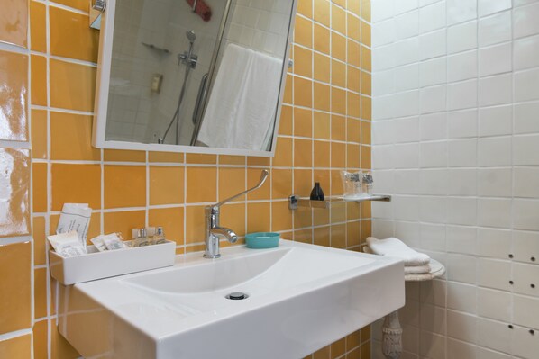 Un baño con un lavamanos blanco, un espejo y baldosas naranjas.