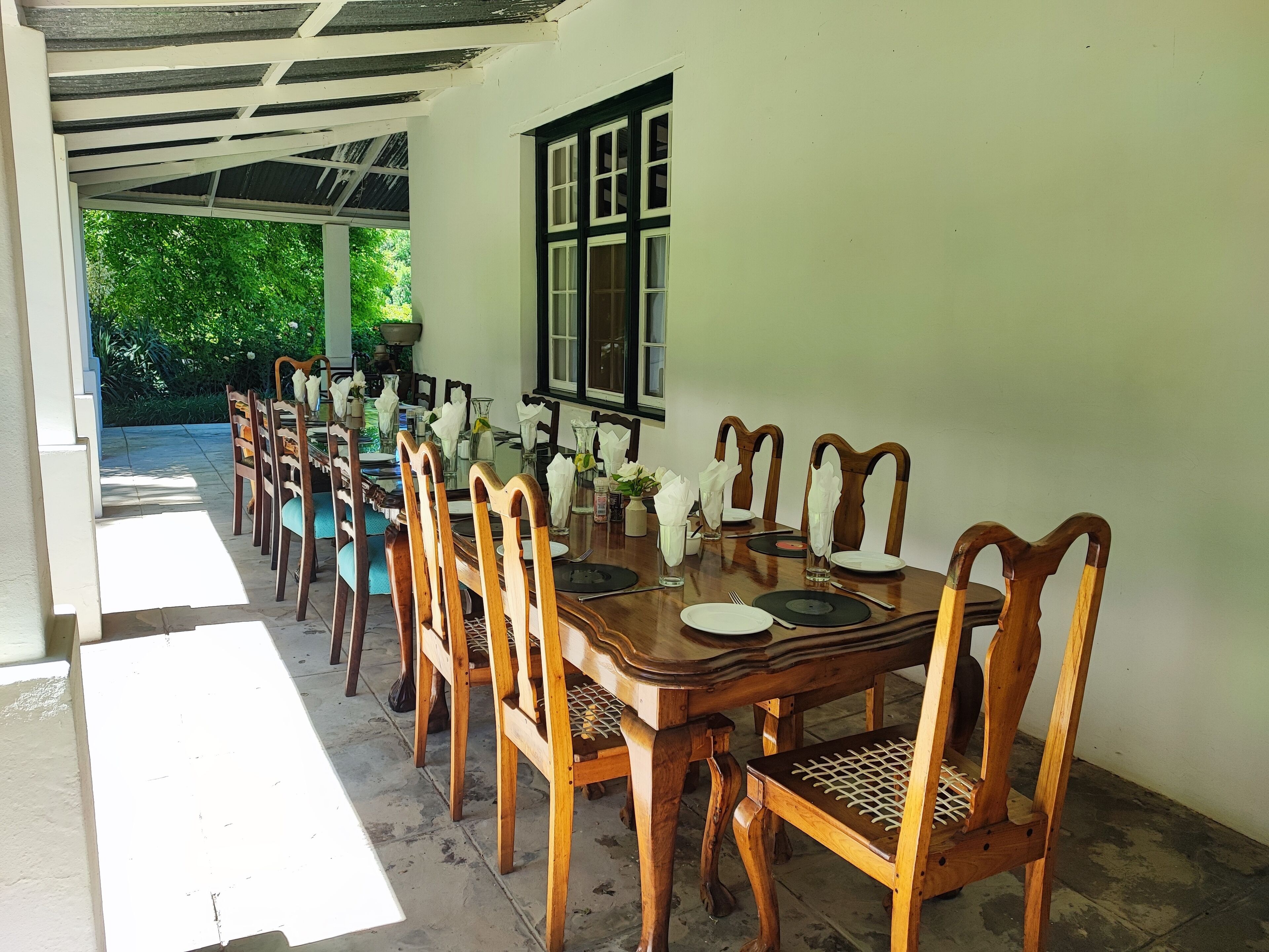 A dining area with a long wooden table set for multiple people, surrounded by wooden chairs with cushioned seats.