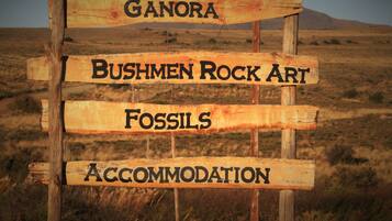 A wooden sign with the words "Ganora," "Bushmen Rock Art," "Fossils," and "Accommodation" indicating points of interest.