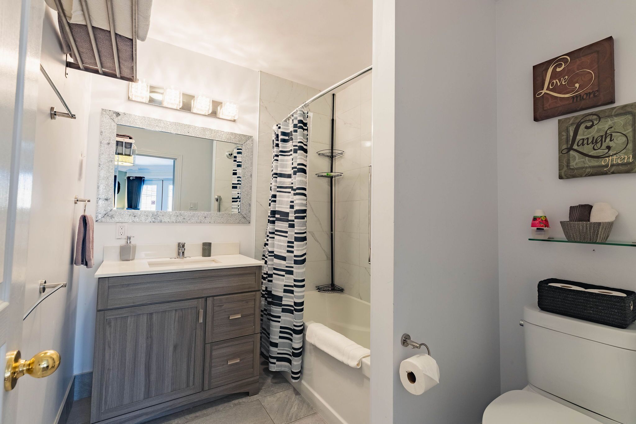 A bathroom with a vanity, a shower, a toilet, and decorative wall art.