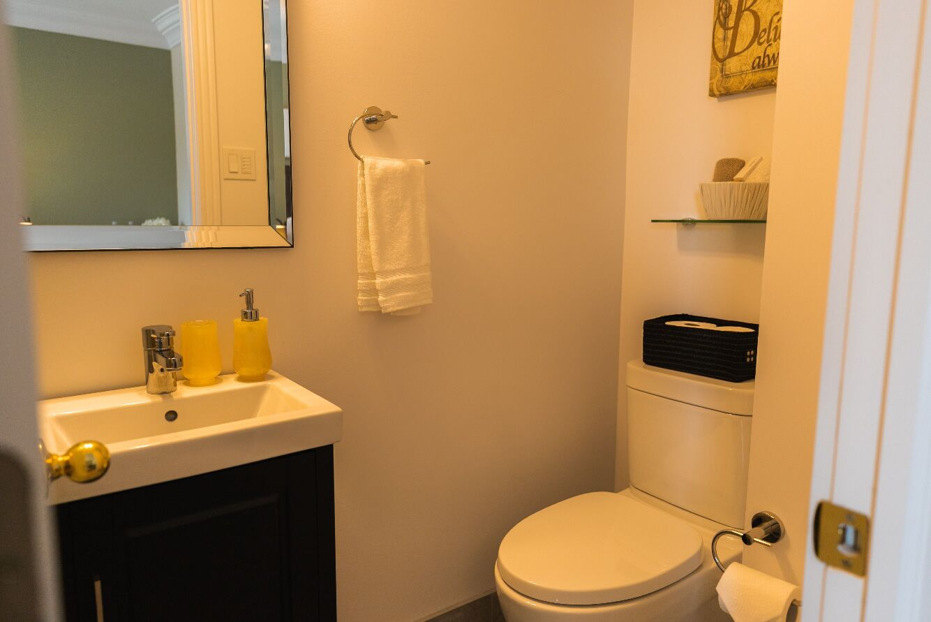 A bathroom with a sink, toilet, and a mirror.