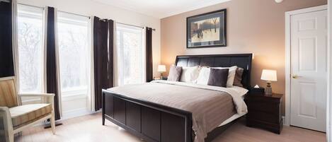 A bedroom with a bed, bedside tables, a chair, and a window with curtains.