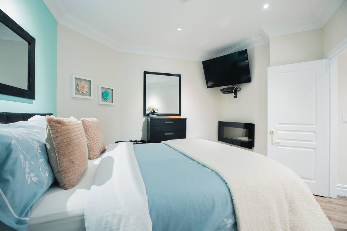 Un dormitorio con cama, cómoda, televisor y puerta.