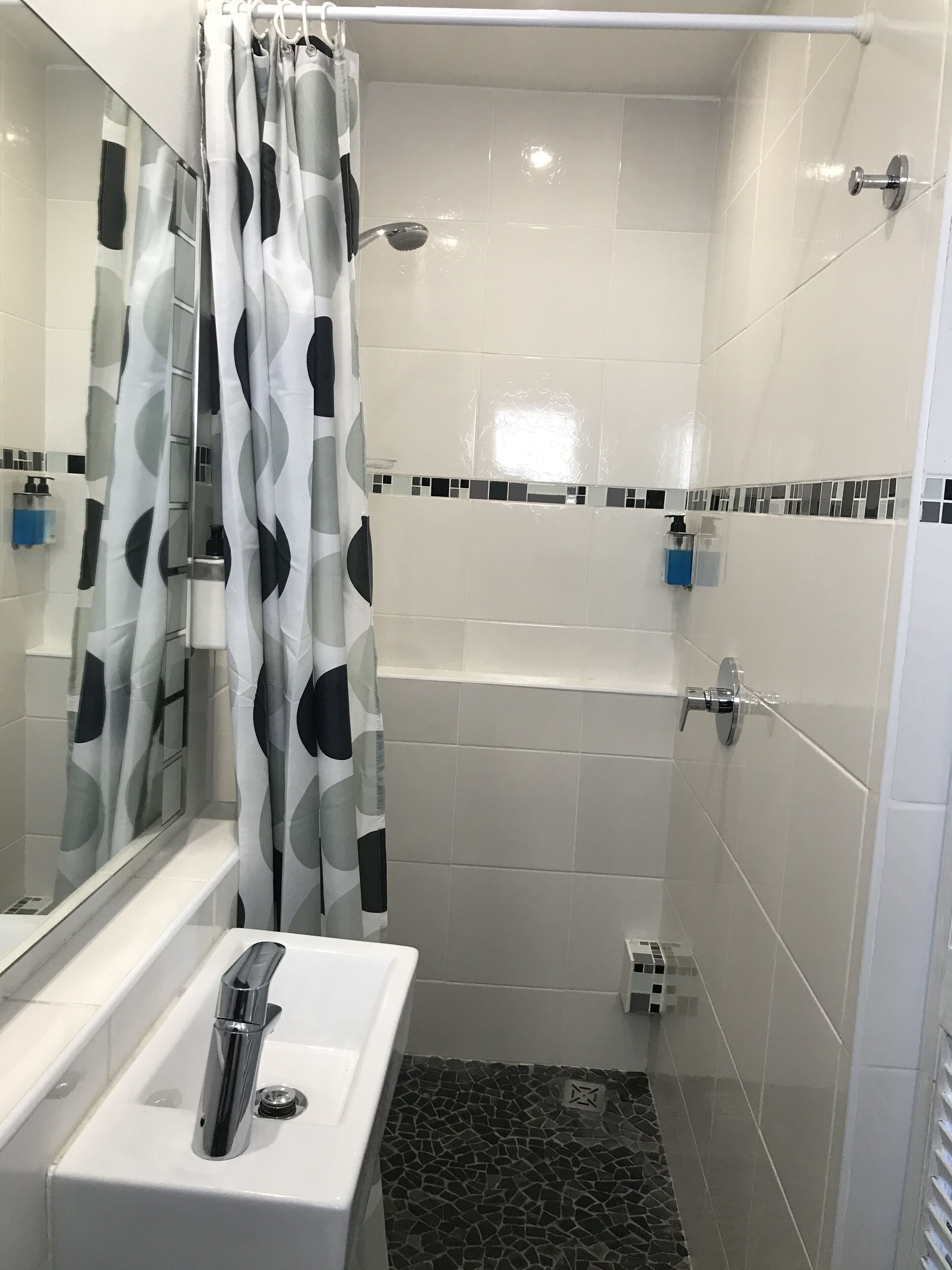 A bathroom with a shower, a sink, and a mirror.