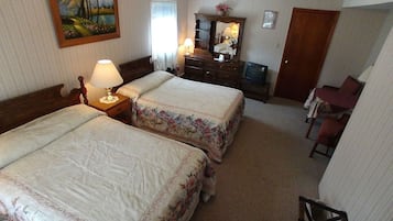 Una habitación de hotel con dos camas, un aparador, un espejo, un televisor y una silla.
