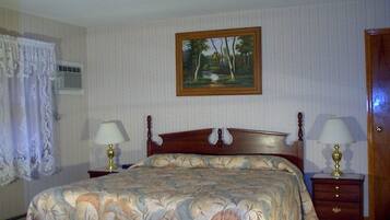 Un dormitorio con una cama grande, dos mesitas de noche con lámparas, un cuadro en la pared y una puerta.