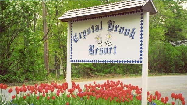 Une enseigne indiquant l’emplacement du Crystal Brook Resort, entourée de tulipes rouges.