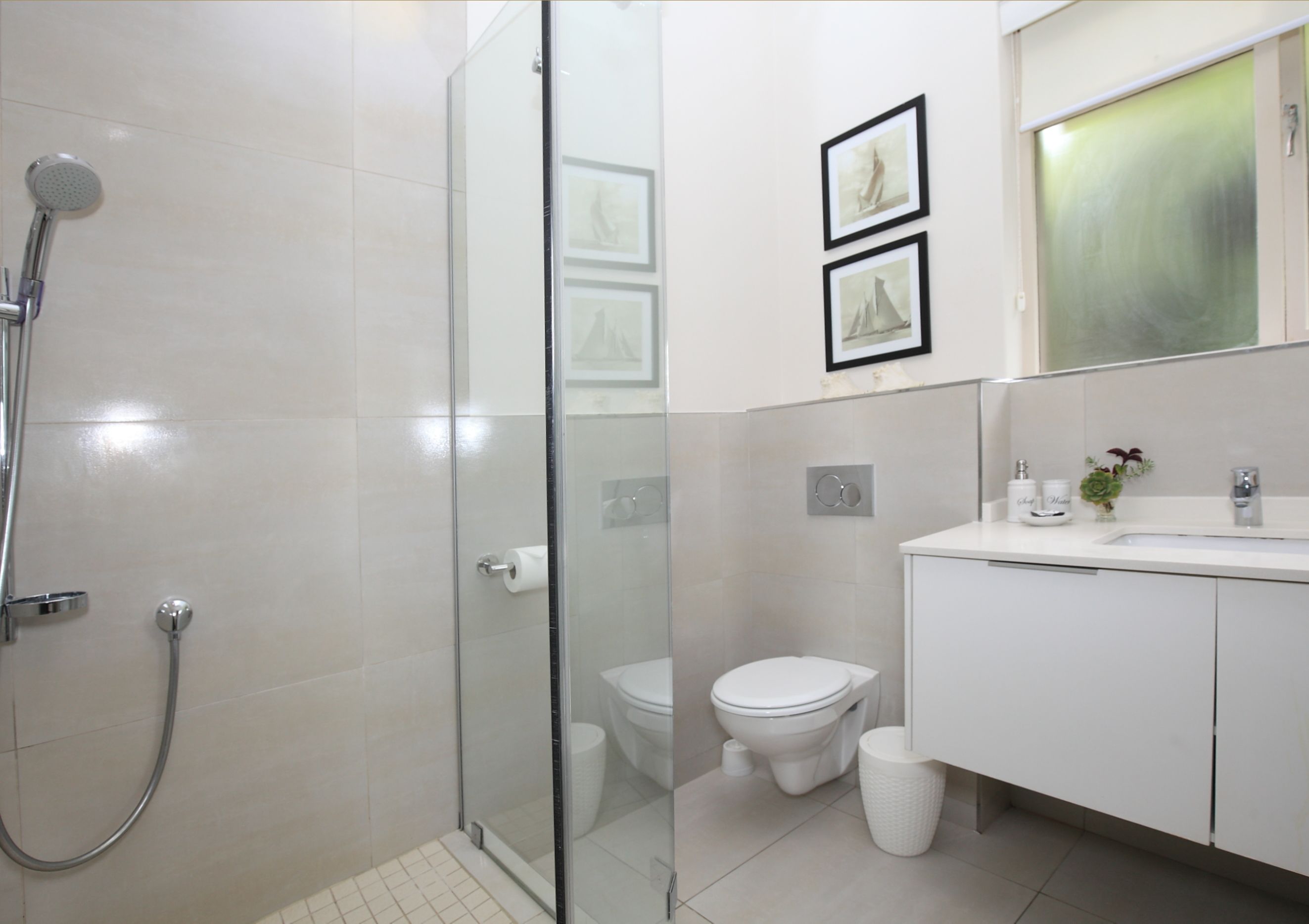 A modern bathroom with a glass-enclosed shower, a toilet, and a sink with a mirror above.
