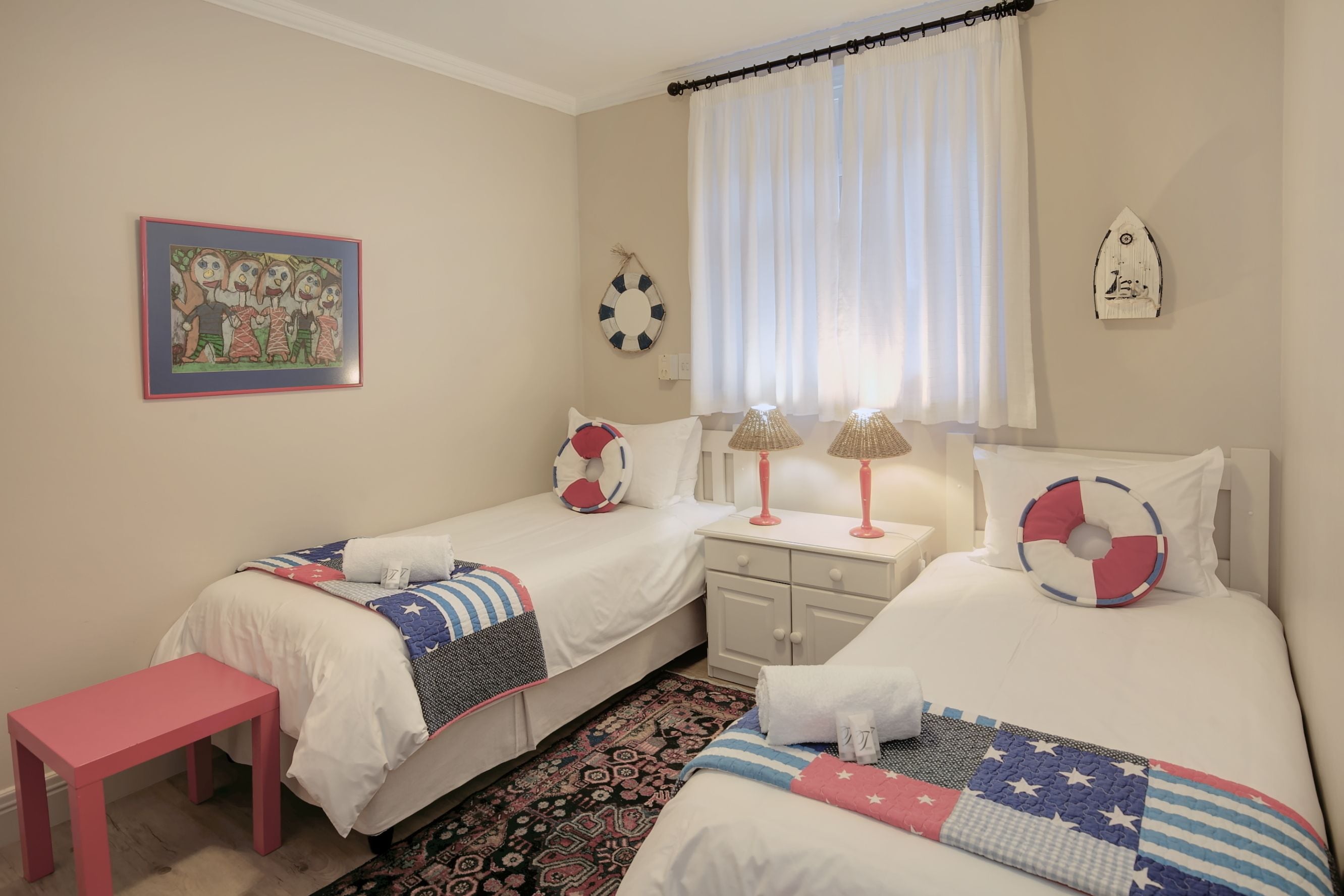 Un dormitorio con dos camas, una mesita pequeña y un banco.