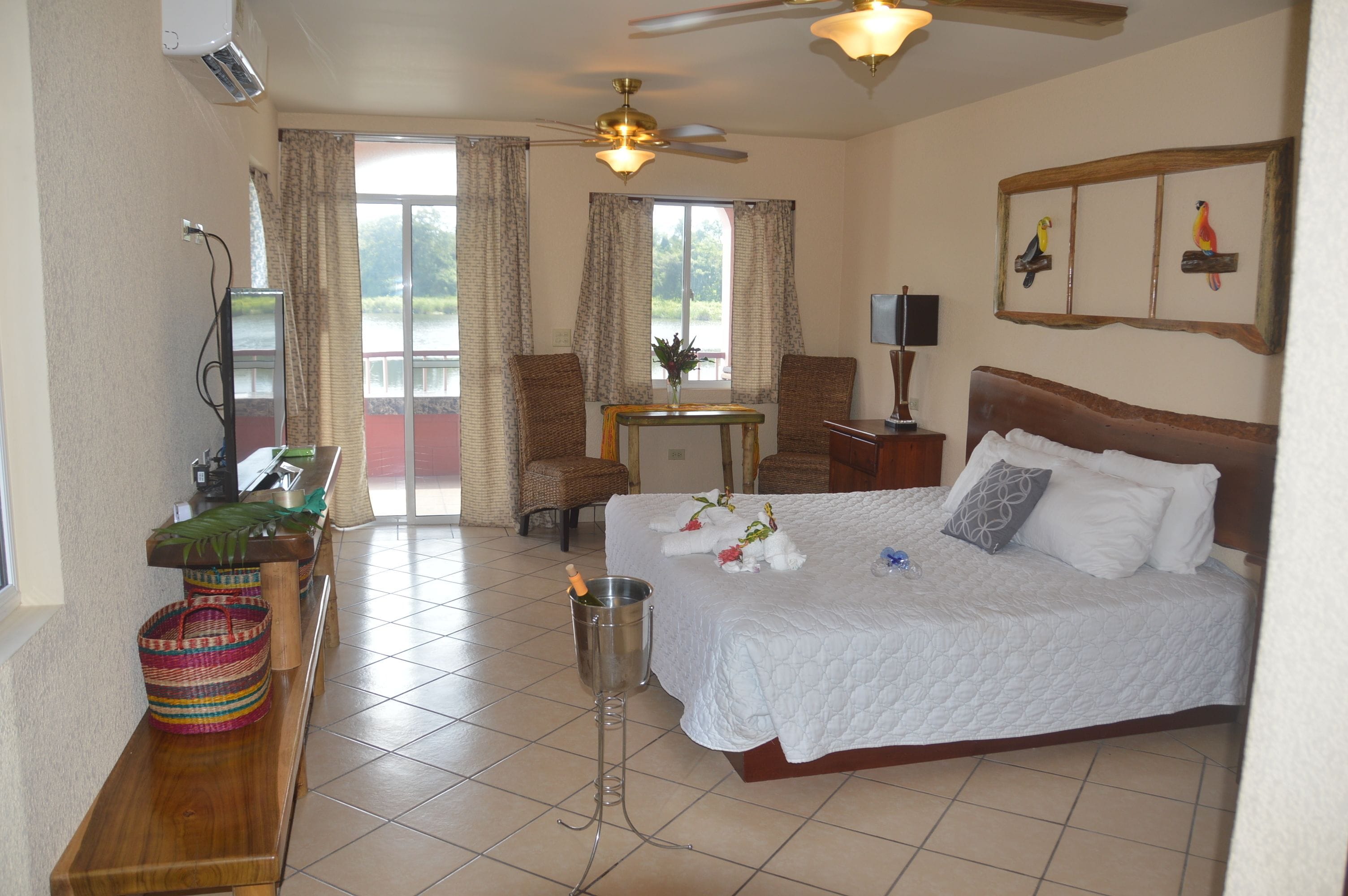 A hotel room with a bed, a desk, a chair, a television, and a balcony with curtains.