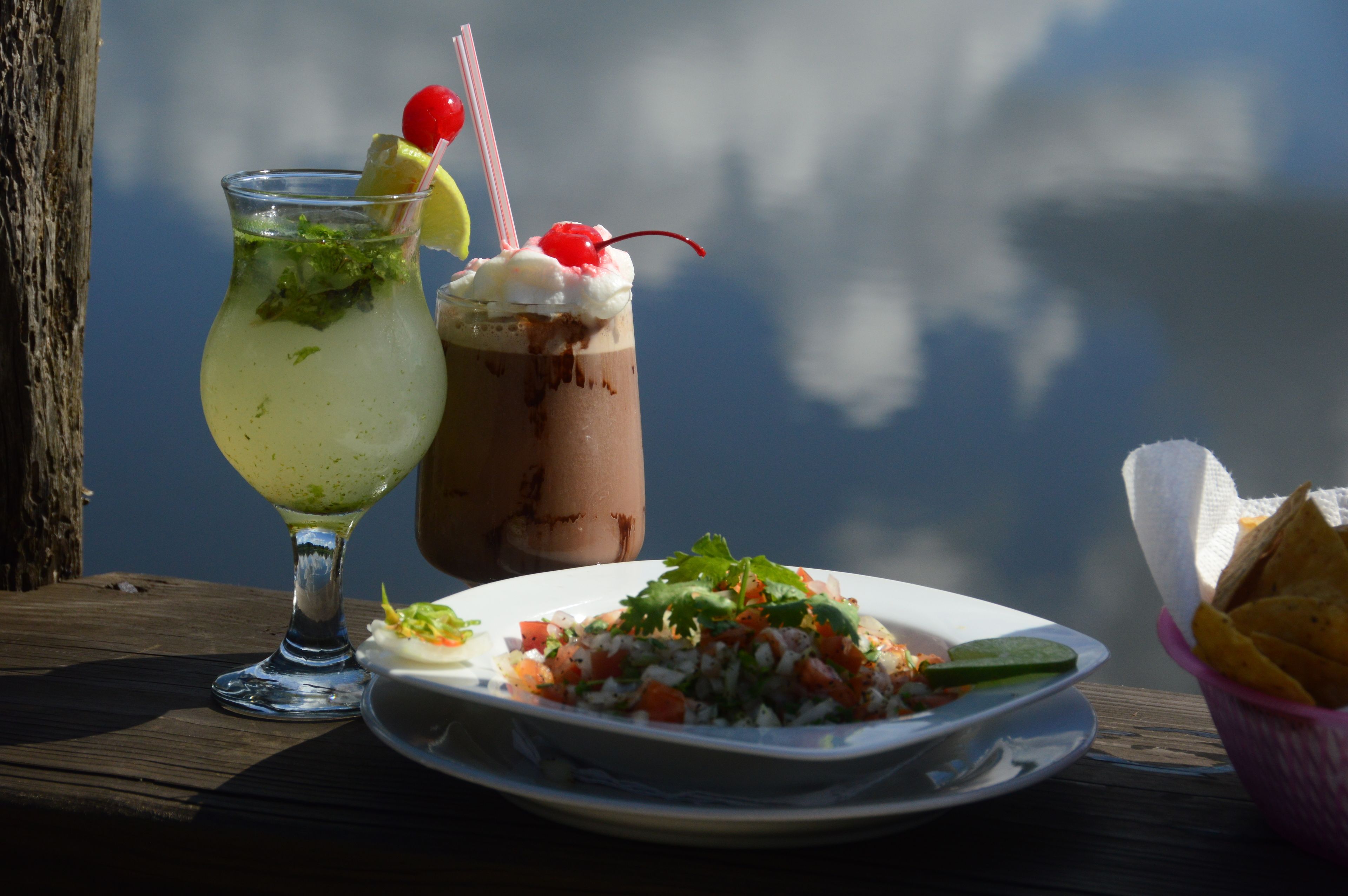 A table with a drink, a dessert, and a plate of food.