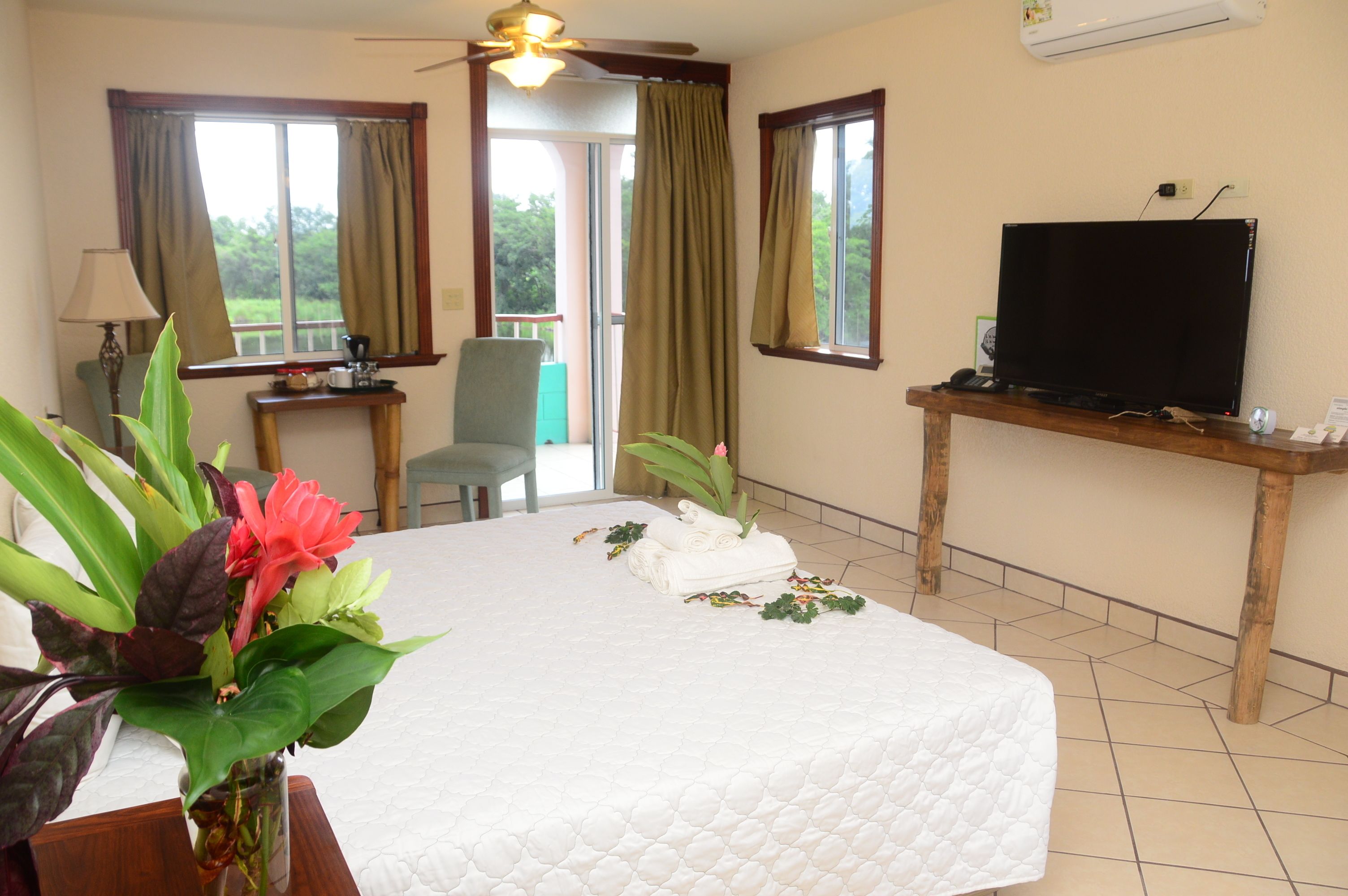 A hotel room with a bed, a television, a desk, and a window with curtains.