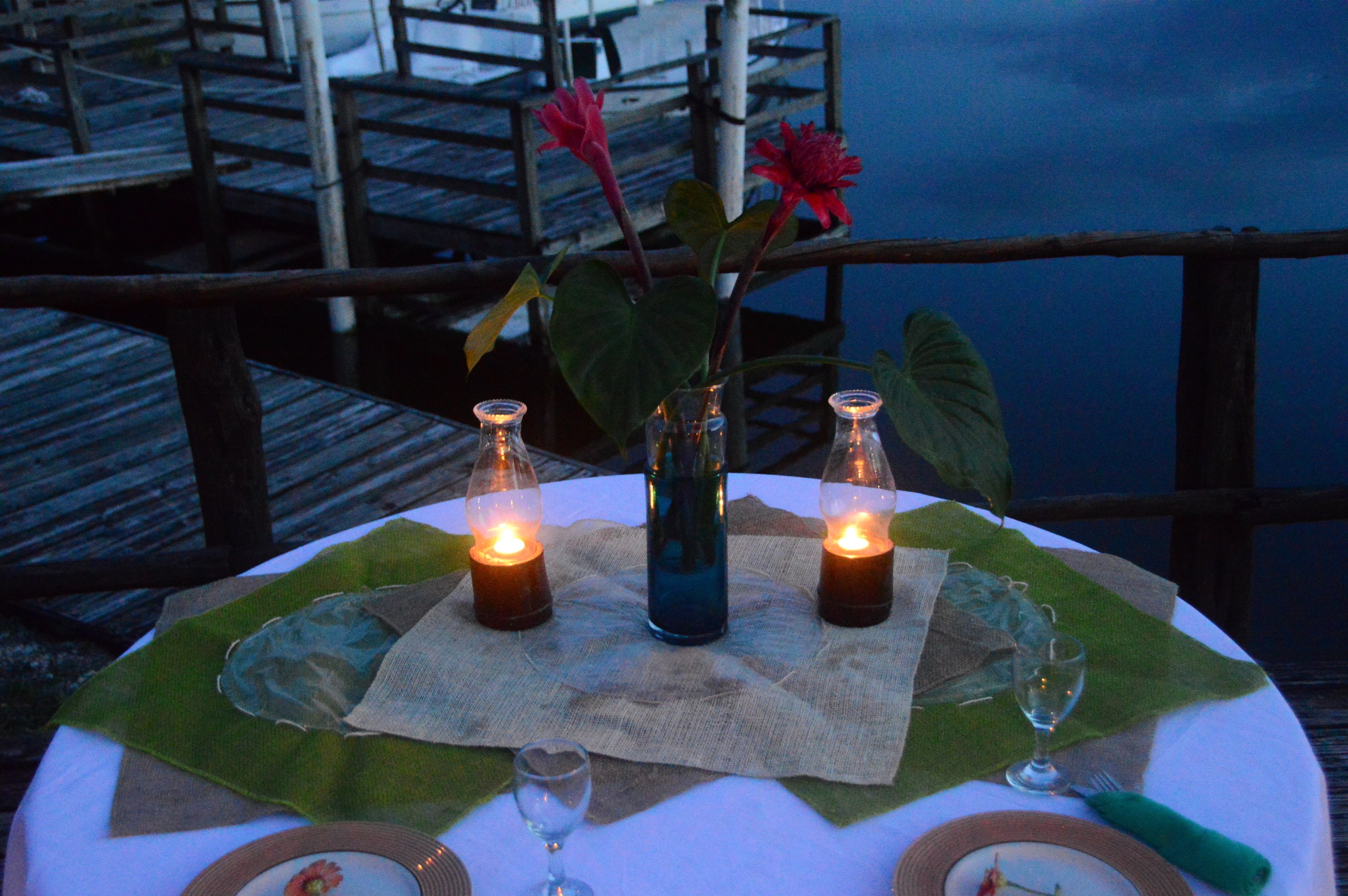 A table set for two with candles, a glass of water, and a plate with a flower.