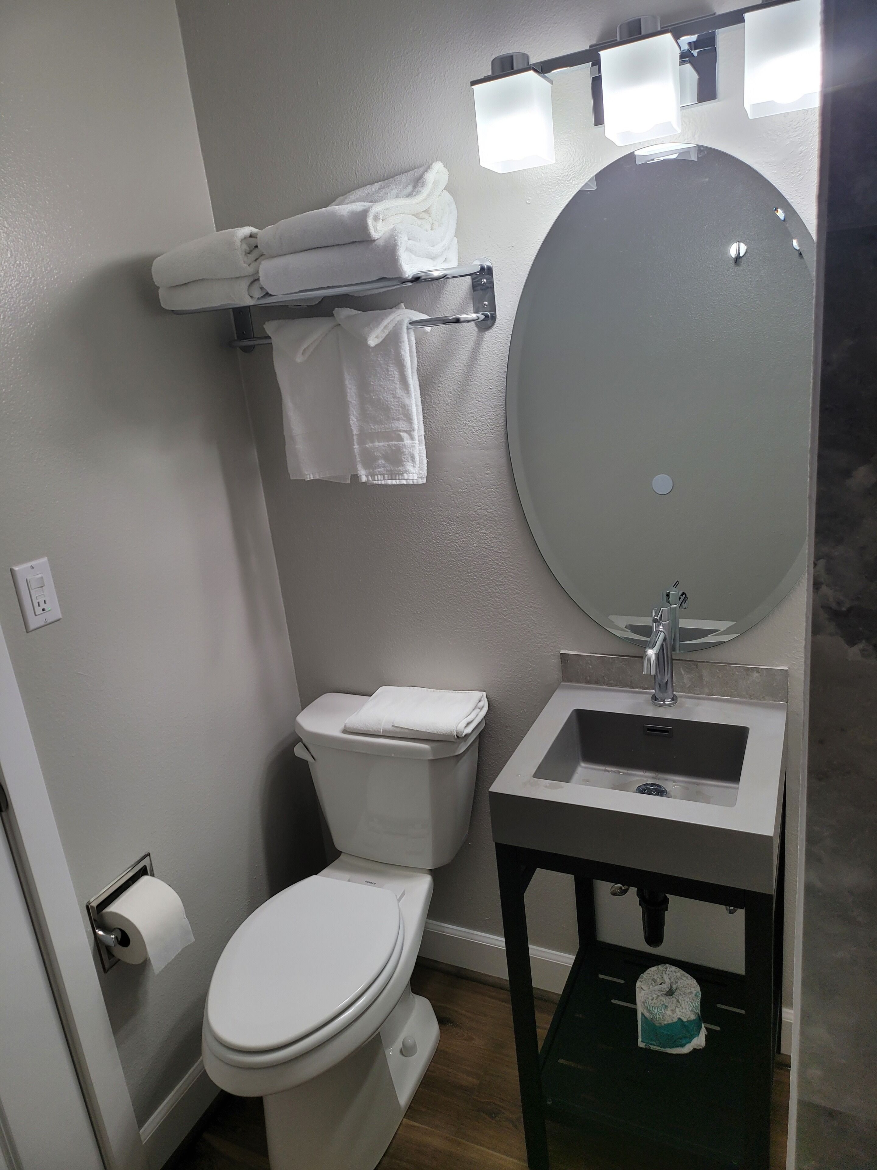 Une salle de bain équipée de toilettes, d’un lavabo, d’un miroir et d’un porte-serviettes.