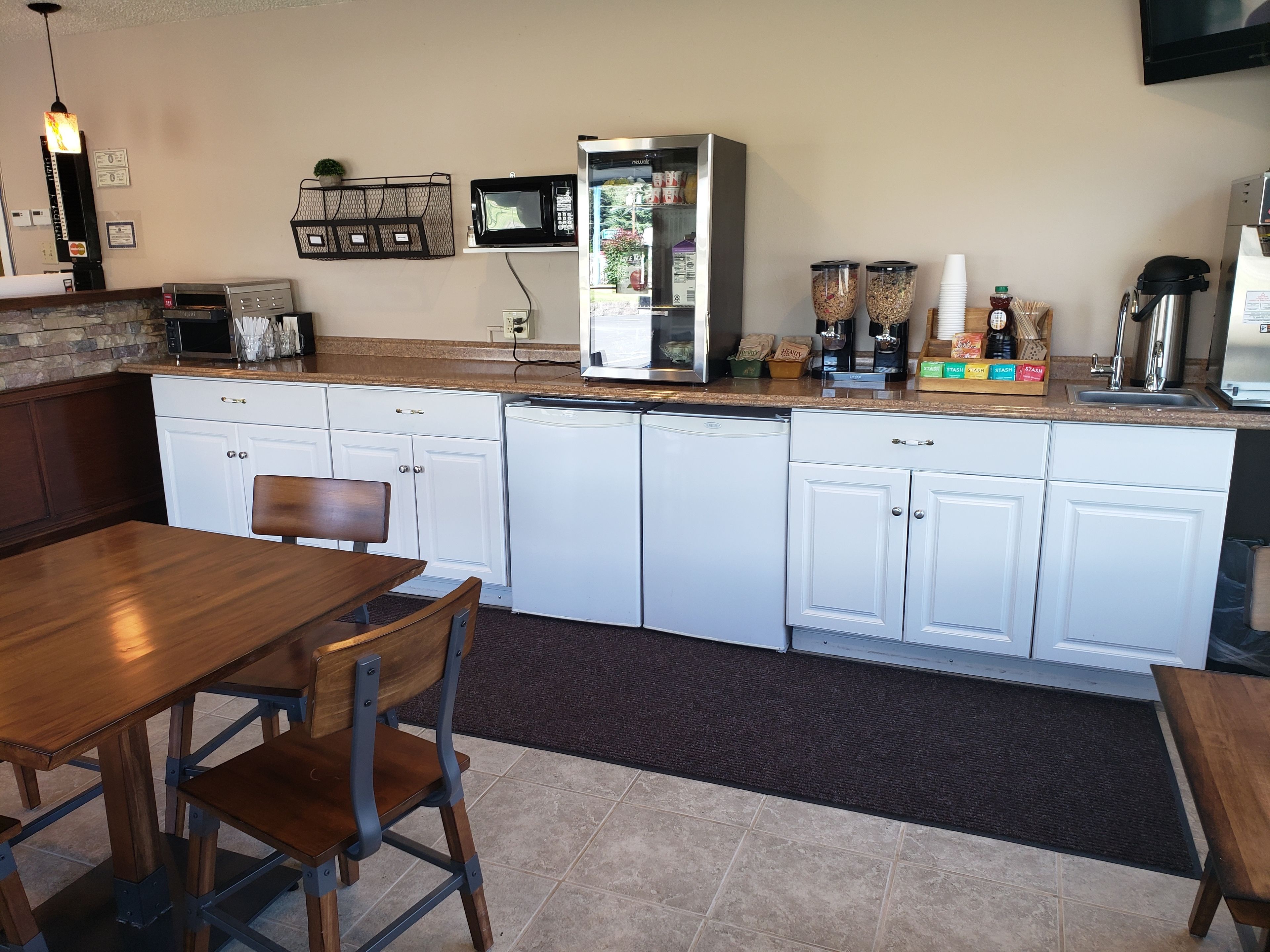 A compact kitchen with white cabinets, a microwave, a coffee machine, and a refrigerator.