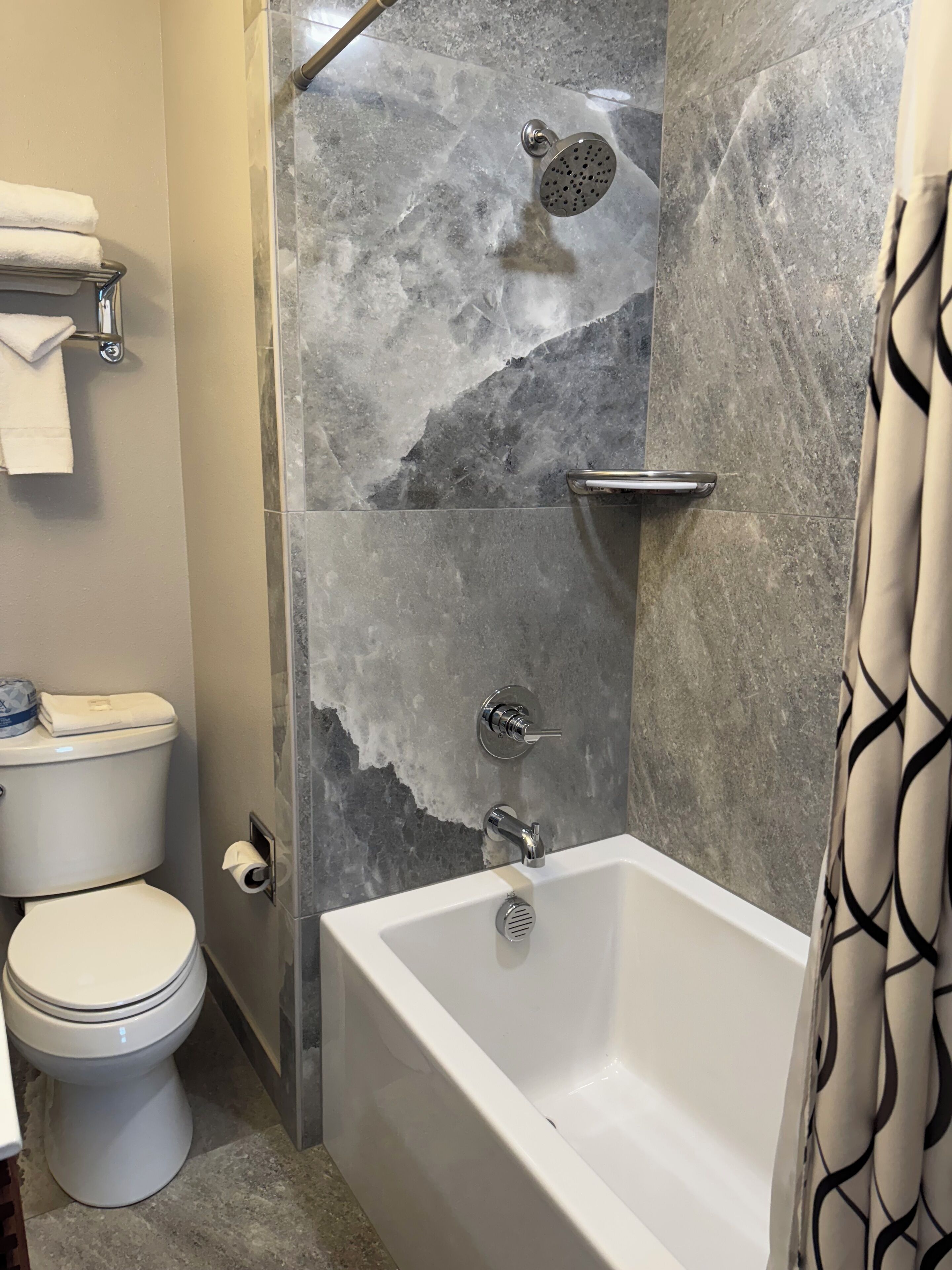 Een badkamer met een bad, toilet en douche.