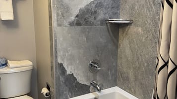 Een badkamer met een bad, toilet en douche.