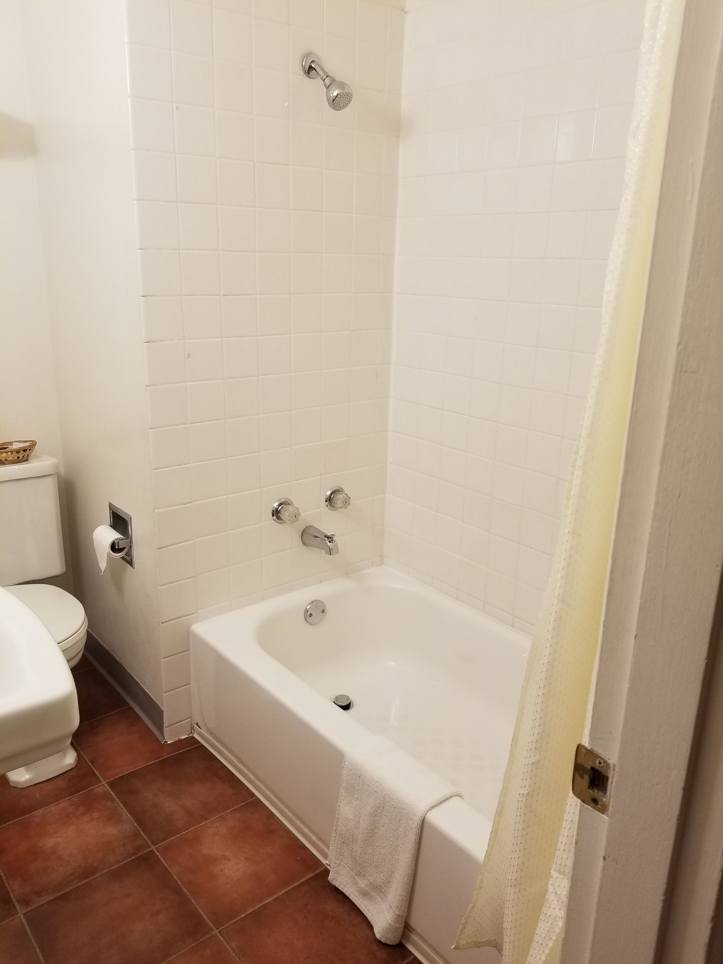 Un baño con una bañera blanca, inodoro y ducha.