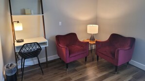 A small, modern room with a wooden desk, two chairs, a lamp, and a mirror. - Bridge Street Inn (Baker City)