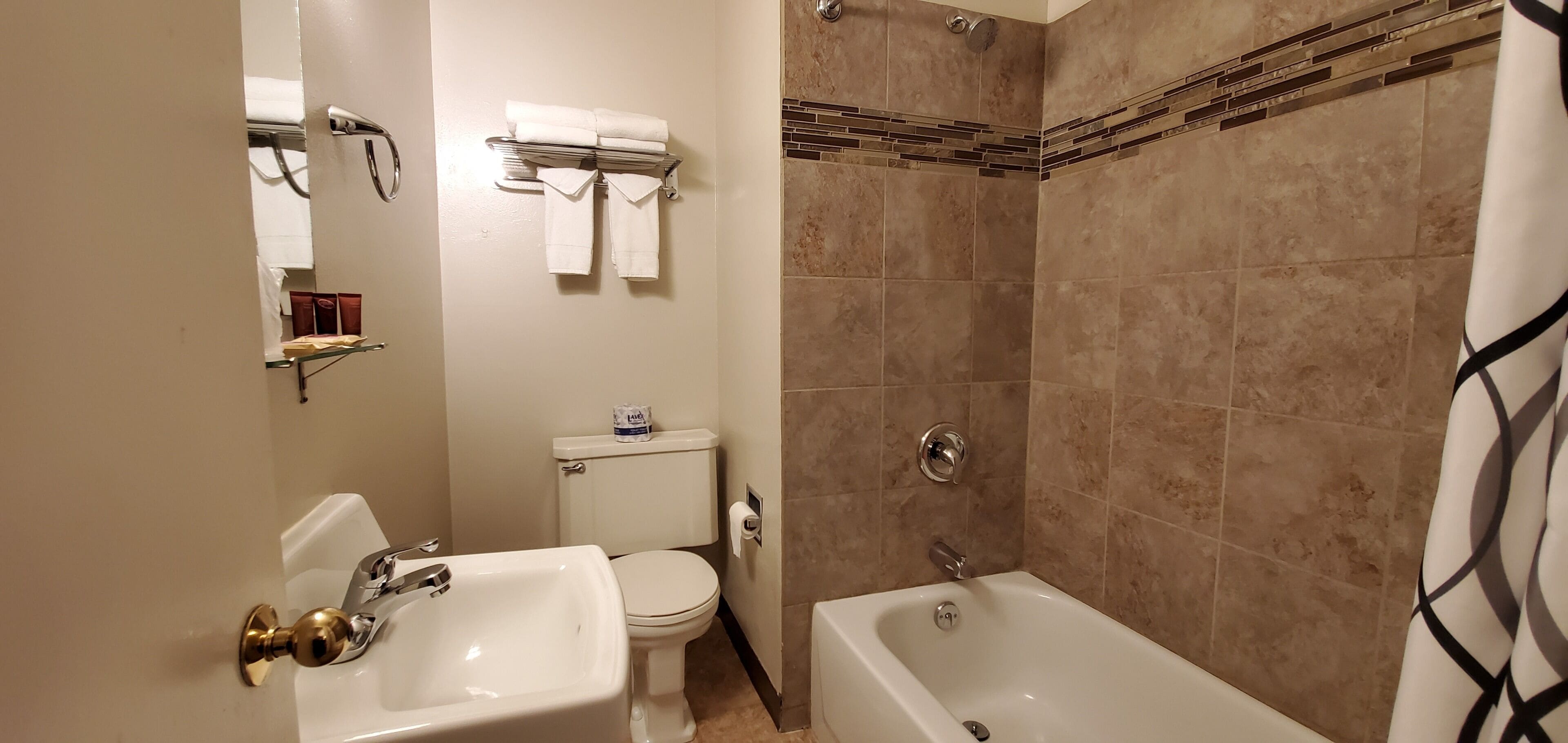 A bathroom with a toilet, sink, bathtub, and a shower area.