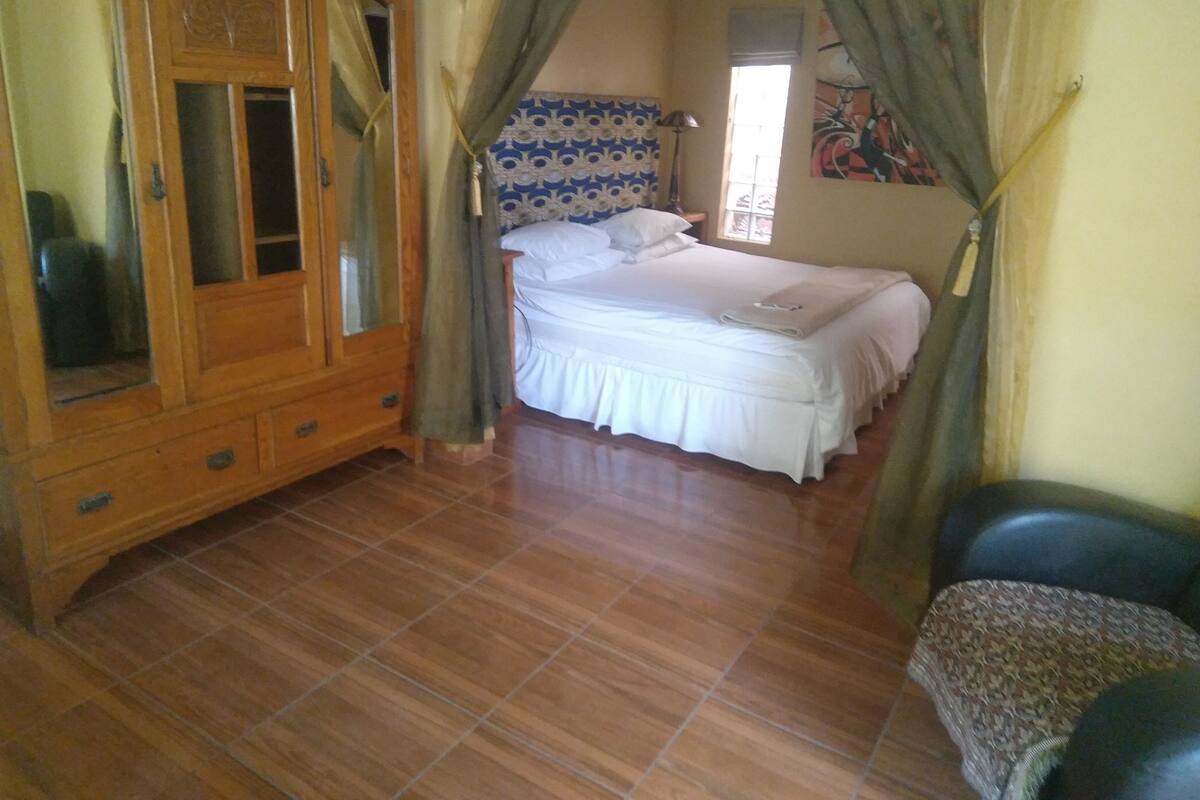 Un dormitorio con cama, armario y ventana.