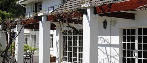 A white building with a tiled roof, large windows, and a covered outdoor seating area.