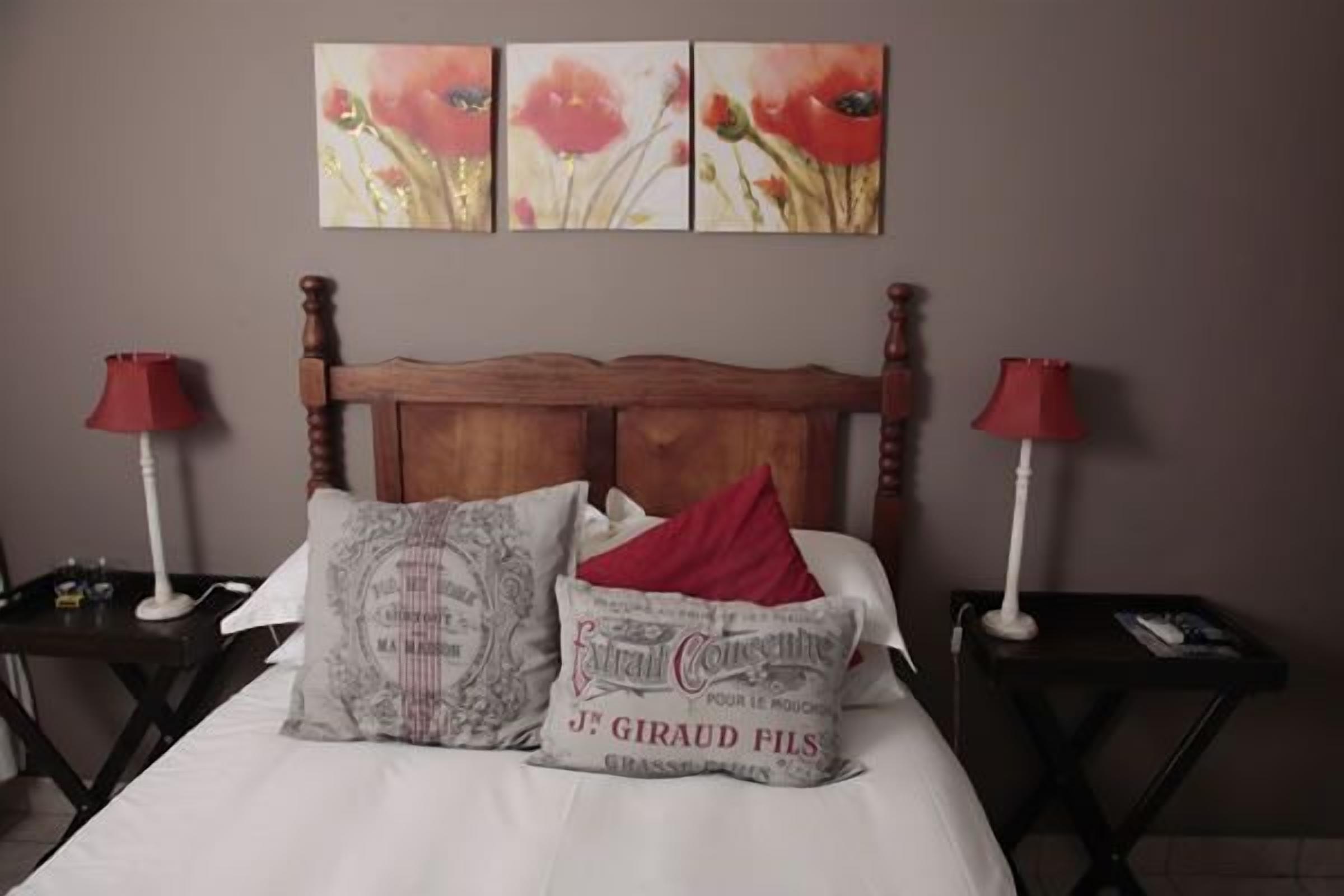 A bedroom with a wooden headboard, two bedside tables with lamps, and a bed with white linens and decorative pillows.