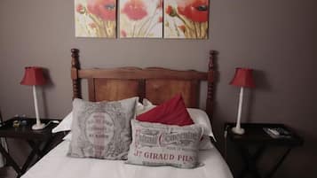 A bedroom with a wooden headboard, two bedside tables with lamps, and a bed with white linens and decorative pillows.