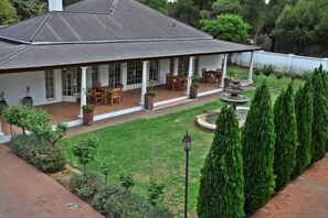 A house with a covered patio, outdoor seating, and a well-maintained lawn. - Lemon & Lime Guest House (Bloemfontein)