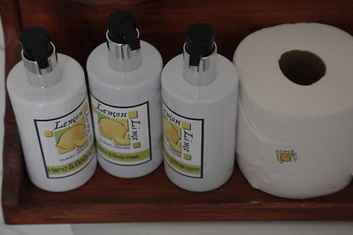 Tres botellas de jabón corporal con sabor a limón y lima, y un rollo de papel higiénico.