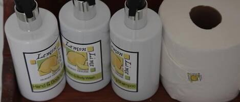 Three bottles of lemon lime body wash and a roll of toilet paper.
