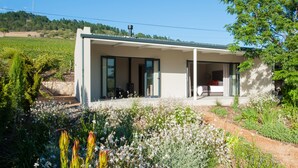 A modern house with a large glass door, a covered porch, and a garden with various plants and flowers.
