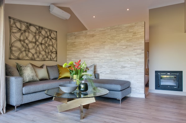 A modern living room with a grey sofa, a glass coffee table, and a decorative vase with flowers. - Jordan Wines Luxury Suites (Stellenbosch)