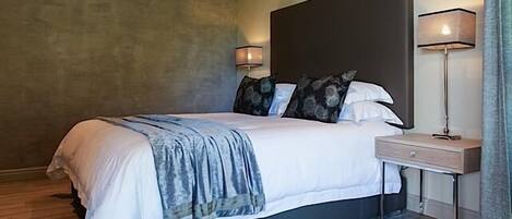 A modern bedroom with a large bed, two bedside lamps, and a nightstand.
