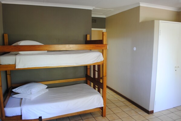 A bunk bed room with a door and a light switch on the wall.