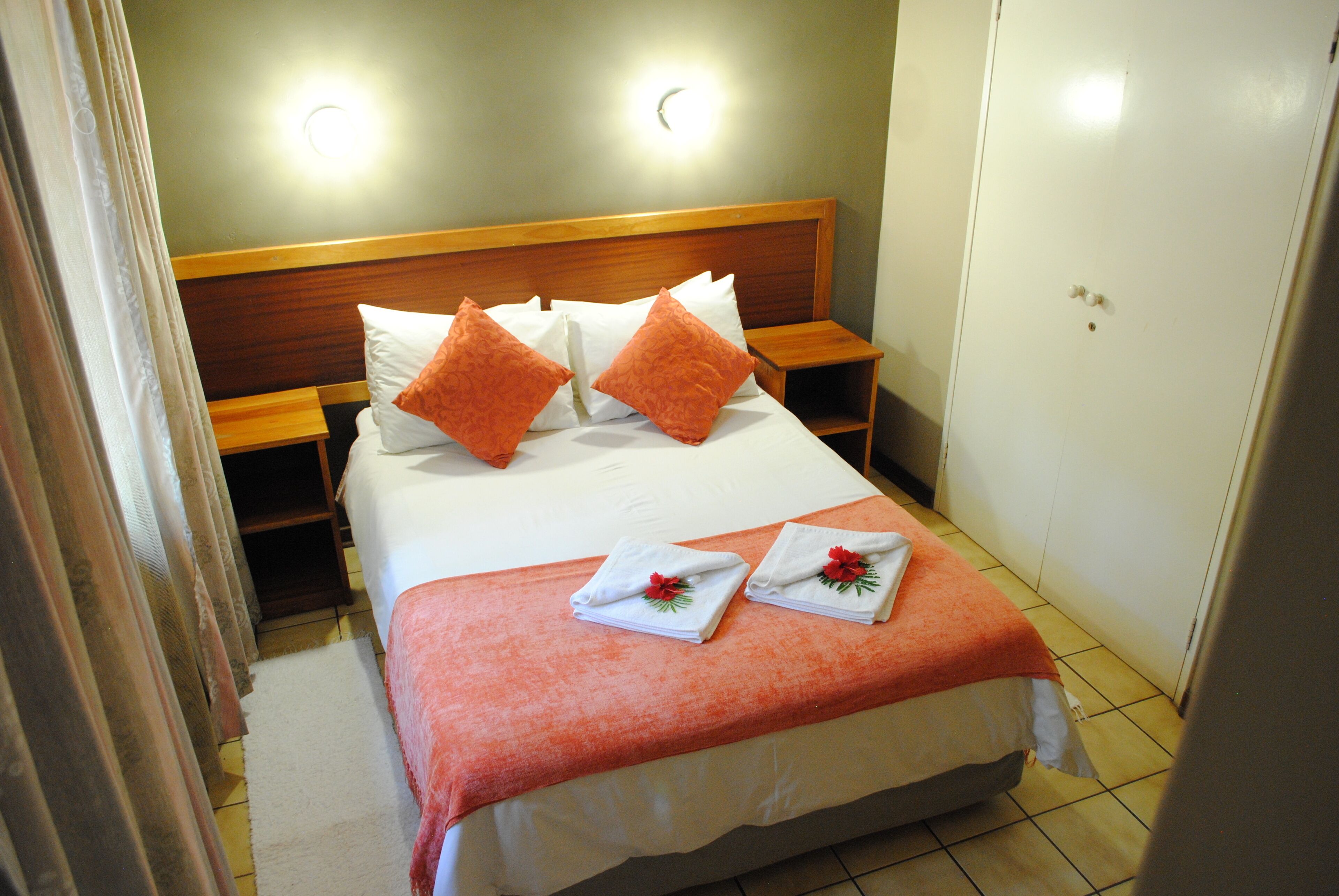 A neatly made bed with a wooden headboard, two bedside tables, and a nightstand.