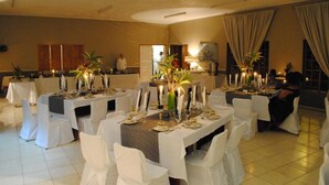 A formal dining area with tables set for multiple guests, featuring white chairs and candle centerpieces. - Eagle's Nest Chalets (Hazy view)