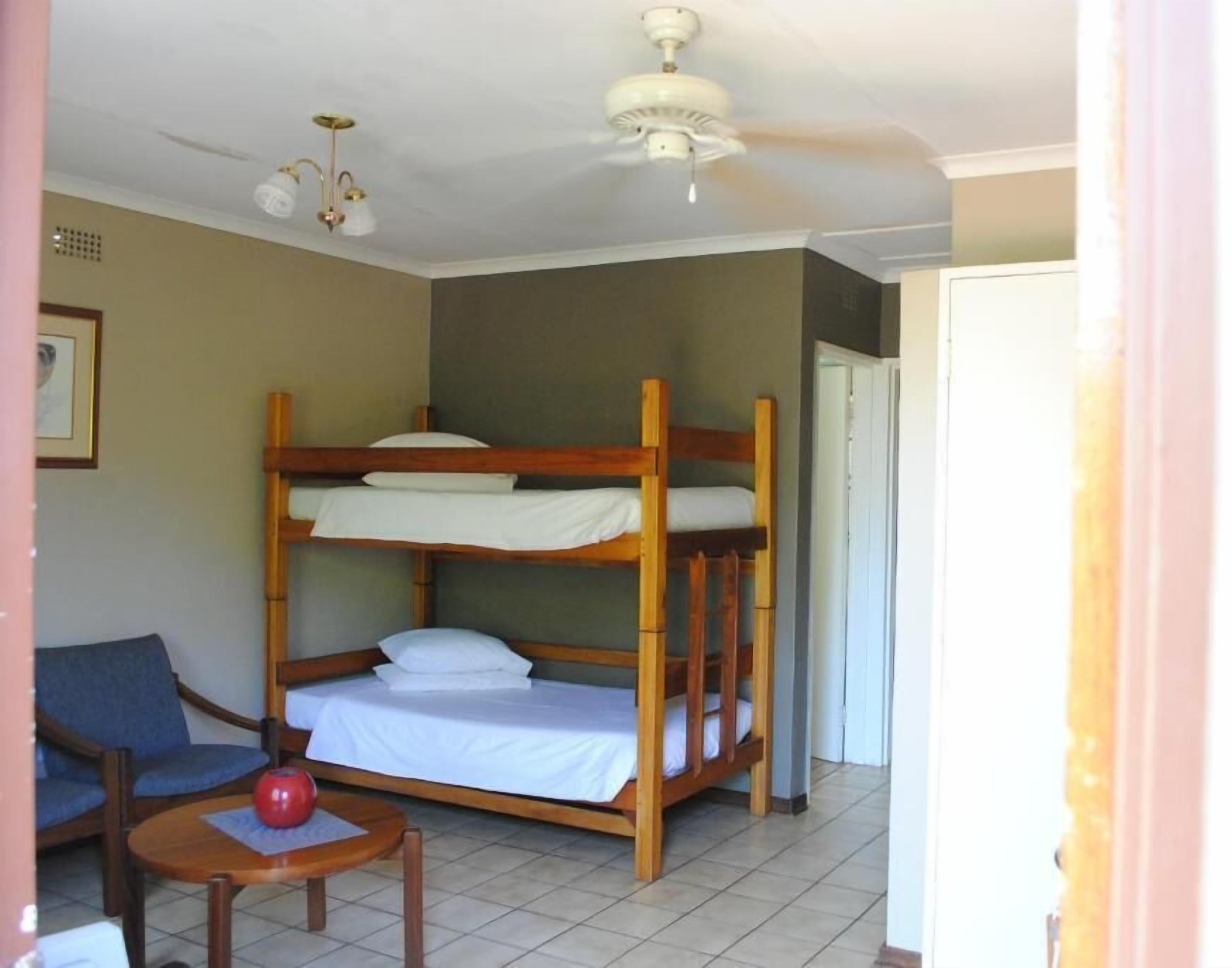 A room with bunk beds, a small table with a red object, and a ceiling fan.