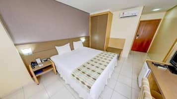 A hotel room with a bed, bedside table, TV, and a wardrobe.