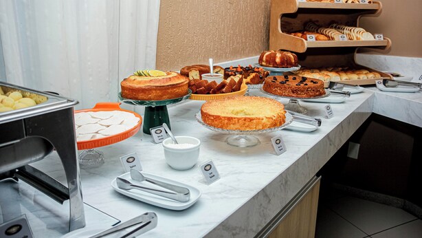 Un bufé con diversos productos de repostería y postres, incluyendo pasteles y dulces, dispuesto sobre una encimera de mármol.