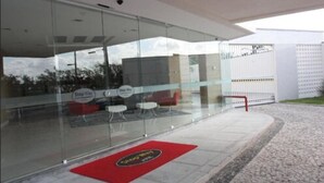 Un edificio moderno con paredes de vidrio, un felpudo rojo en la entrada y un cartel que dice 'Stop Way'.