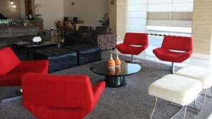Una sala de estar moderna con muebles rojos y blancos, una mesa de centro de vidrio y vistas a través de amplios ventanales.