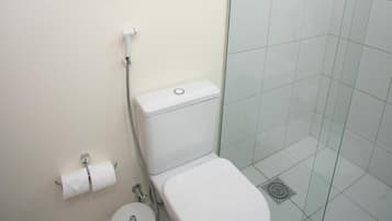 A small, modern bathroom with a glass shower enclosure, a toilet, and a towel rack with two towels.