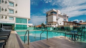 A rooftop pool area with lounge chairs and a clear view of the city skyline. - Varadero Palace Hotel (Florianópolis)
