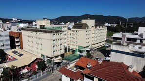 Un hotel a più piani con piscina sul tetto, circondato da altri edifici e con montagne sullo sfondo.