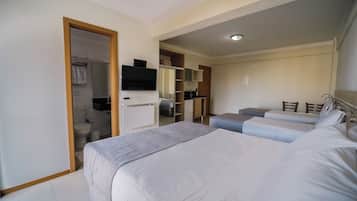 A hotel room with two beds, a bathroom, a kitchenette, and a television.