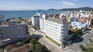 Un paysage urbain côtier avec un grand hôtel blanc qui se distingue, doté de balcons et offrant une vue sur la mer.