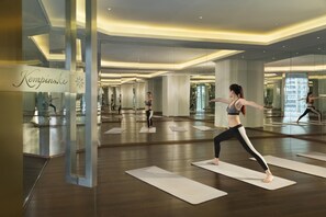 Une salle de sport spacieuse, dotée de nombreux tapis de yoga, de miroirs et d’un aménagement intérieur moderne.